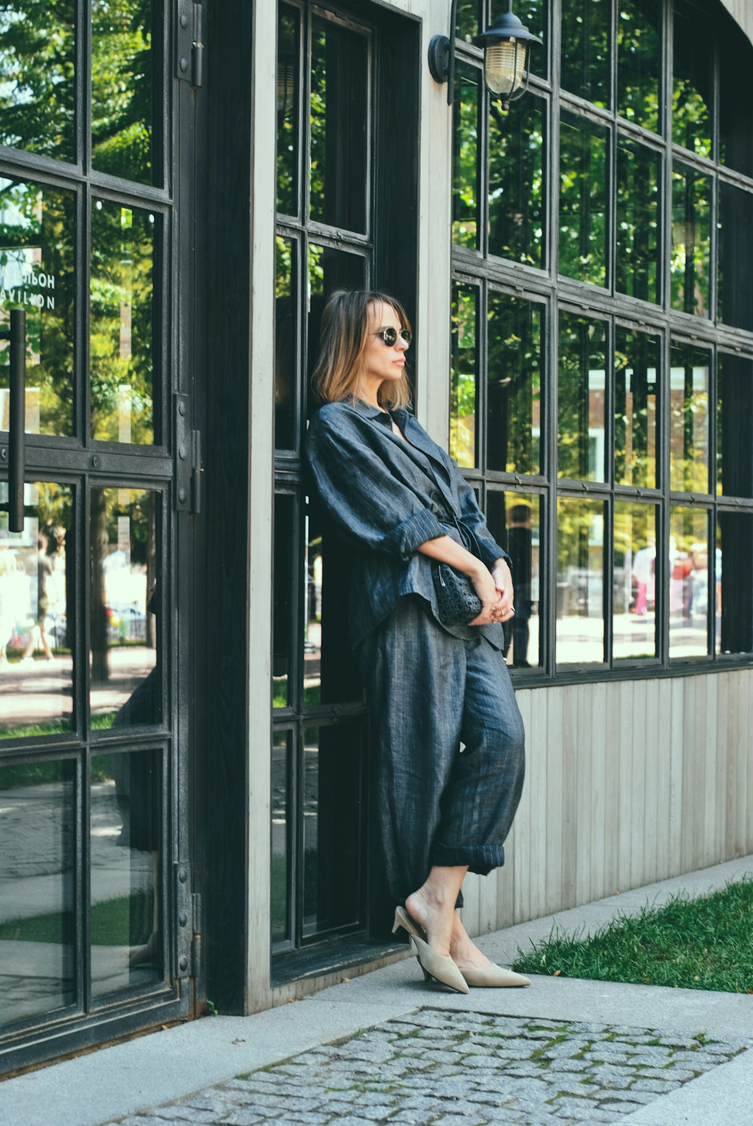 Woman in chic outfit leans by a window