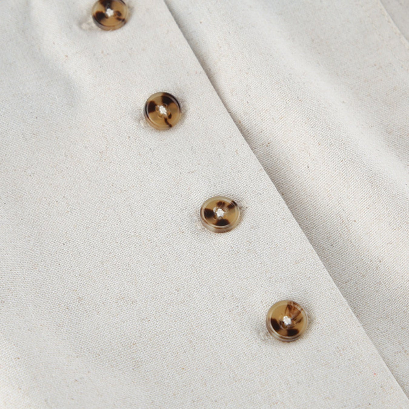 Close-up of a white fabric with gold buttons on a black background
