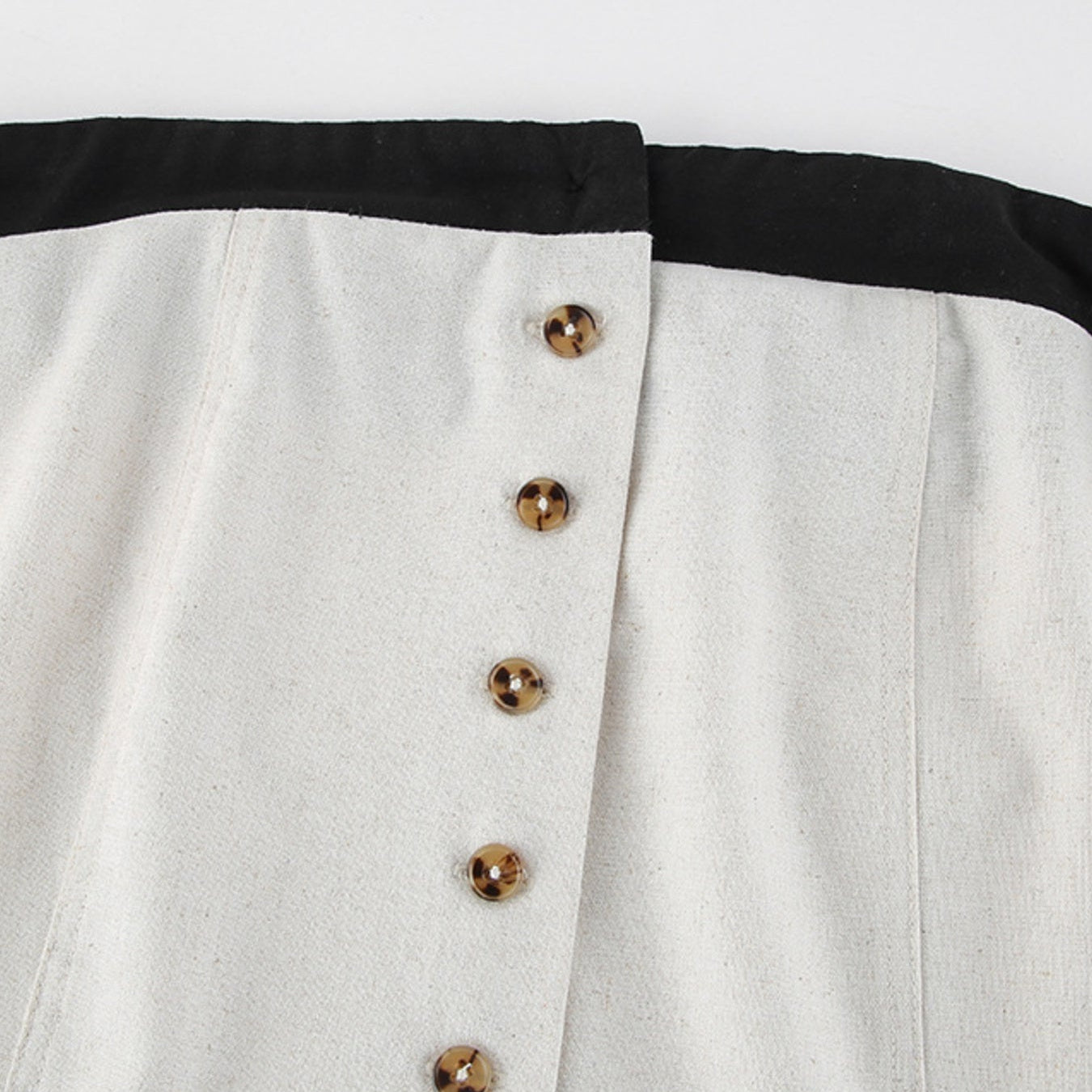 Close-up of a white shirt with black collar and buttons on a light gray background