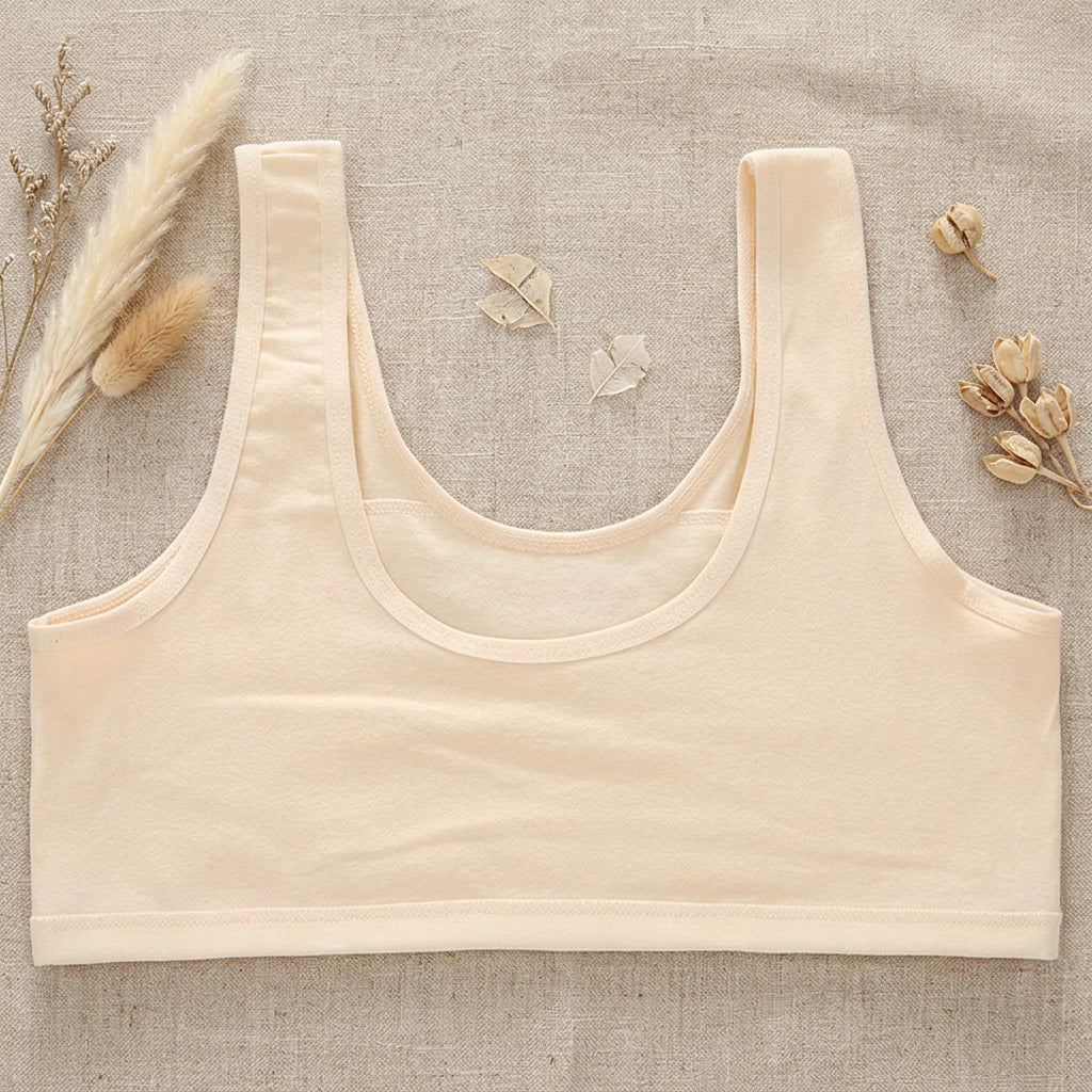 A light beige scoop-neck bralette with wide shoulder straps, laid flat against a solid mint green background.