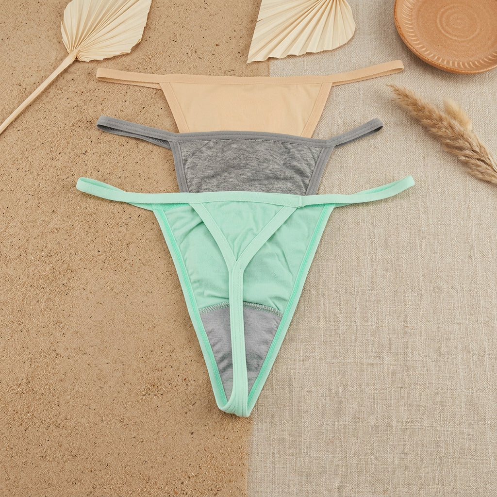 Three pairs of women's thong-style underwear laid flat on a gray background, stacked vertically. The top pair is nude beige, the middle is heather gray with a gray waistband, and the bottom is mint green with a gray waistband.